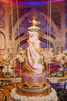 a multi - tiered cake is decorated with gold, pink and blue icing