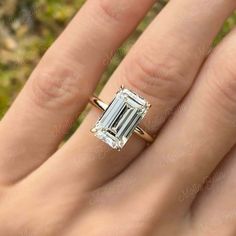 a woman's hand with a ring on it and an emerald stone in the middle