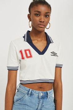 a woman wearing a white shirt and blue jeans with the number 10 on her chest