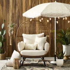 a rattan chair with an umbrella and pillows in front of a wood paneled wall