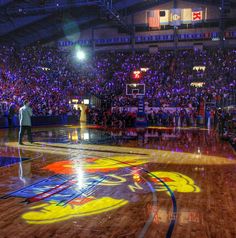 a man standing on top of a basketball court in front of an arena filled with people