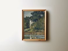 a painting hanging on the wall next to a white wall with a tree and house in it