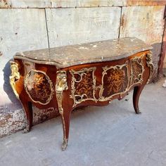 an old wooden table with ornate carvings on the top and bottom, sitting against a wall