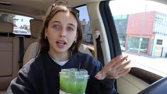 a woman holding a drink in her hand while sitting in the back seat of a car