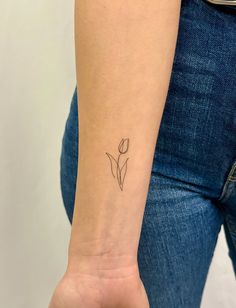 a woman's arm with a single flower tattoo on it