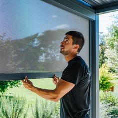 a man standing in front of a sliding glass door with his hand on the window sill