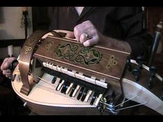 a man is playing an instrument made out of wood and metal pipes with green designs on it