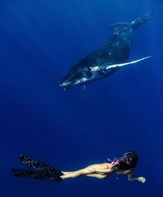 a woman swimming in the ocean next to a whale