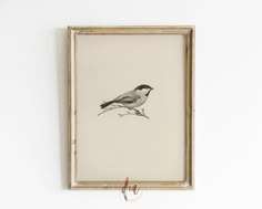 a bird sitting on top of a branch in front of a framed wall art piece