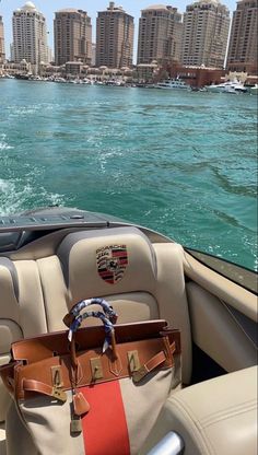 a purse sitting on the back of a boat in front of a cityscape