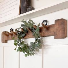 a wooden coat rack holding a wreath on it's side with hooks hanging from it