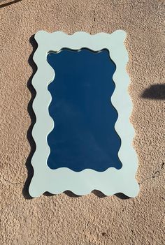 a blue mirror sitting on the side of a wall next to a shadow cast object