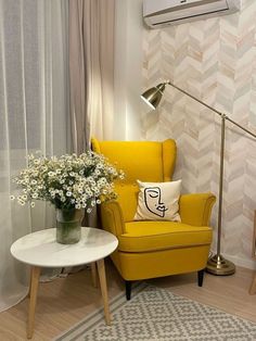 a yellow chair and table with flowers on it in front of a wall mounted air conditioner