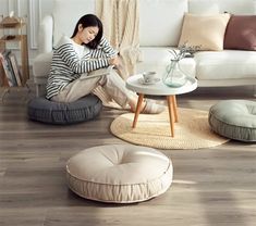 a woman sitting on the floor in front of a white couch with pillows and a coffee table