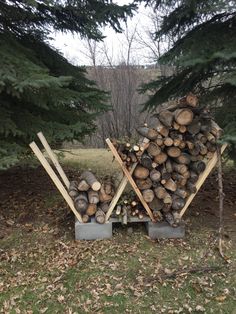 a pile of wood sitting in the middle of a field next to some pine trees