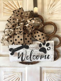 a welcome sign with a dog bone and paw print on it hanging from a door