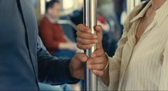 the man and woman are holding hands on the bus together, both looking at each other