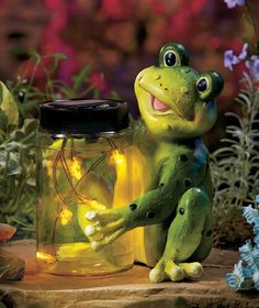 a frog sitting next to a jar filled with lights