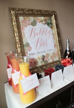 a table topped with lots of bottles of wine next to a sign that says bubbly bar