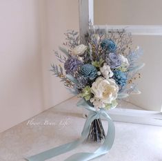 a bouquet of flowers sitting on top of a counter next to a mirror with blue ribbon