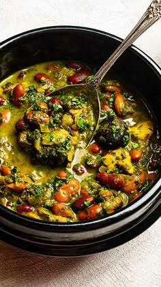 a black bowl filled with stew and vegetables