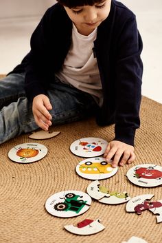 a young boy sitting on the floor playing with some magnets that are shaped like animals