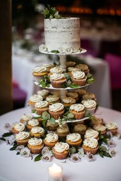 three tiered cake and cupcakes on a table