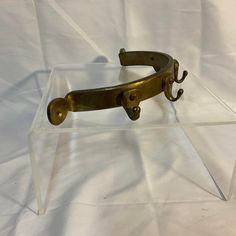 an antique brass pair of scissors on a clear acrylic display stand with white background