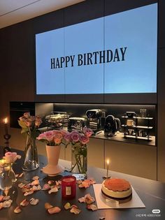 there is a birthday cake on the table with flowers and candles in front of it