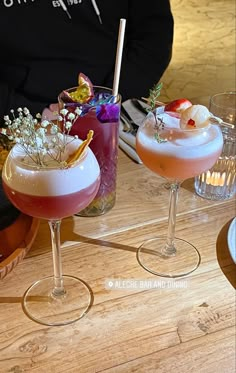 two cocktails sitting on top of a wooden table