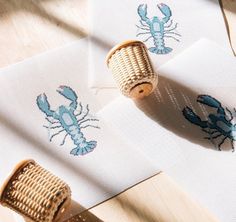 two pieces of fabric with lobsters on them next to a pair of sewing needles