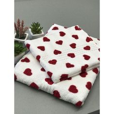 two red hearts on white towels next to succulents and a potted plant