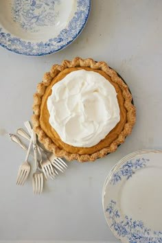 an overhead view of a pie with whipped cream on top and two forks next to it