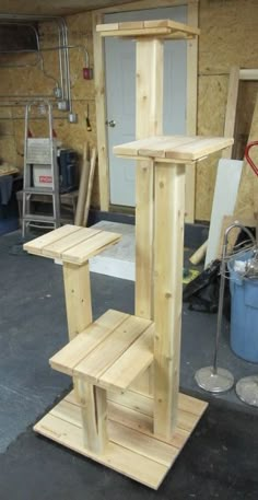 a wooden bird house sitting on top of a stand in a garage next to a blue bucket