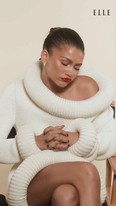 a woman in white sweater and skirt sitting on chair