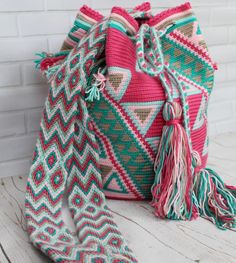 a colorful bag sitting on top of a wooden table next to a brick wall and floor