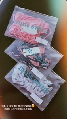 three clear bags filled with pink and blue hair ties on top of a black table