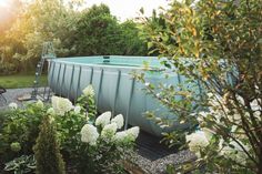 an above ground pool surrounded by plants and flowers