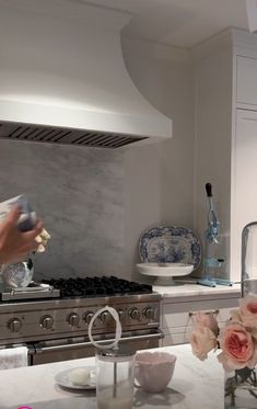 a woman is in the kitchen with flowers on the counter and an oven behind her