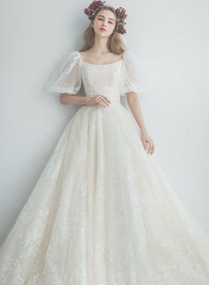 a woman in a wedding dress with flowers on her head standing against a white wall