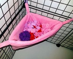 a pink hammock filled with purple and red tissue paper in the corner of a room