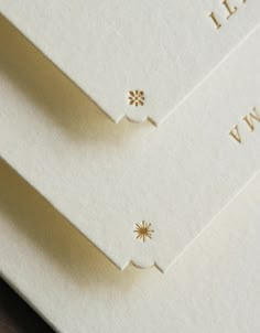 two white envelopes with gold embellishments on the front and back of them