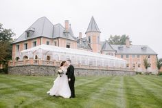 a bride and groom standing in front of a large building with a glass greenhouse on the lawn