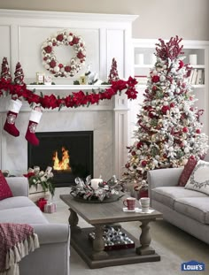 a living room decorated for christmas with red and white decorations on the fireplace mantel