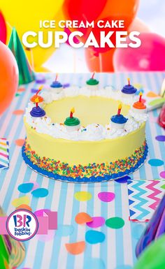 an ice cream cake with candles on it surrounded by balloons and streamers in the background