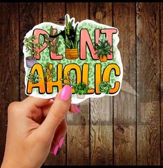 a person holding up a sticker with the words plantaholic on it in front of a wooden wall