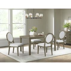 a dining room table with white chairs and a rug in front of the window,