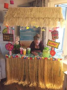 a woman sitting at a table in front of a tiki hut filled with drinks