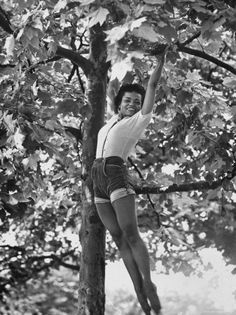 an old photo of a woman climbing up a tree