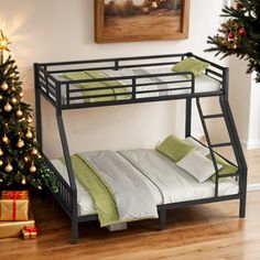 a bunk bed sitting next to a christmas tree in a room with wooden flooring